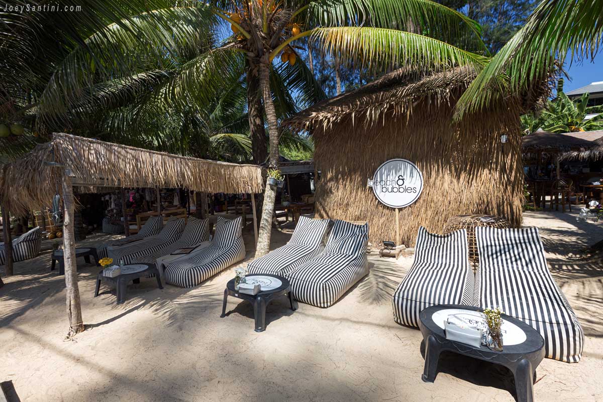 Showing two loungers and two talbes with a bamboo hut bheind