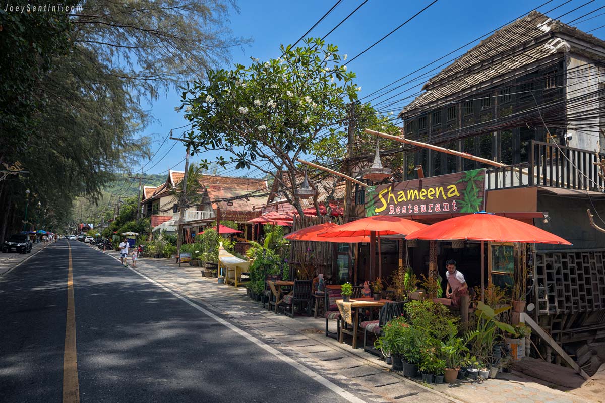 Showing restaurant with tree red umbrellas and small green plants