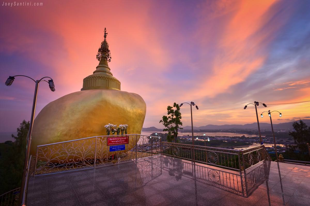 The Golden Rock chedi replica at Wat Koh Siray glowing under a dramatic pink and orange sunset sky in Phuket