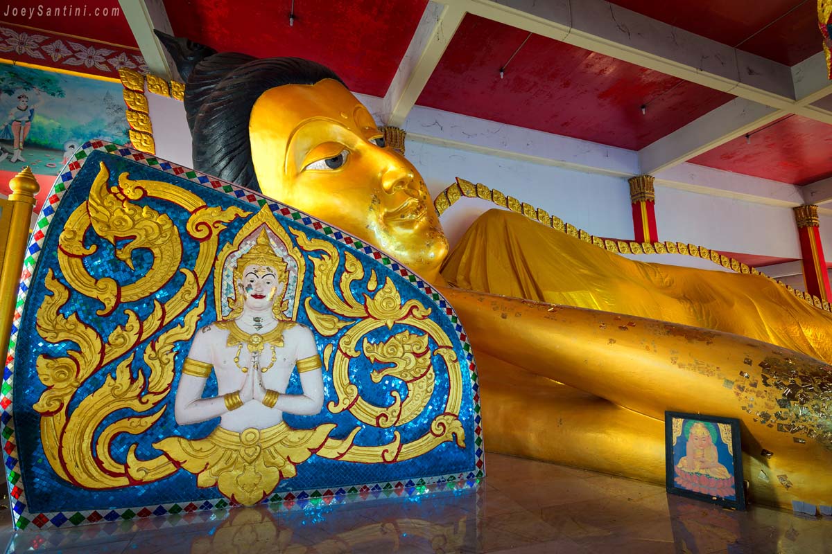 Close-up of the ornate mosaic pillow supporting the giant golden reclining Buddha statue at Wat Koh Siray