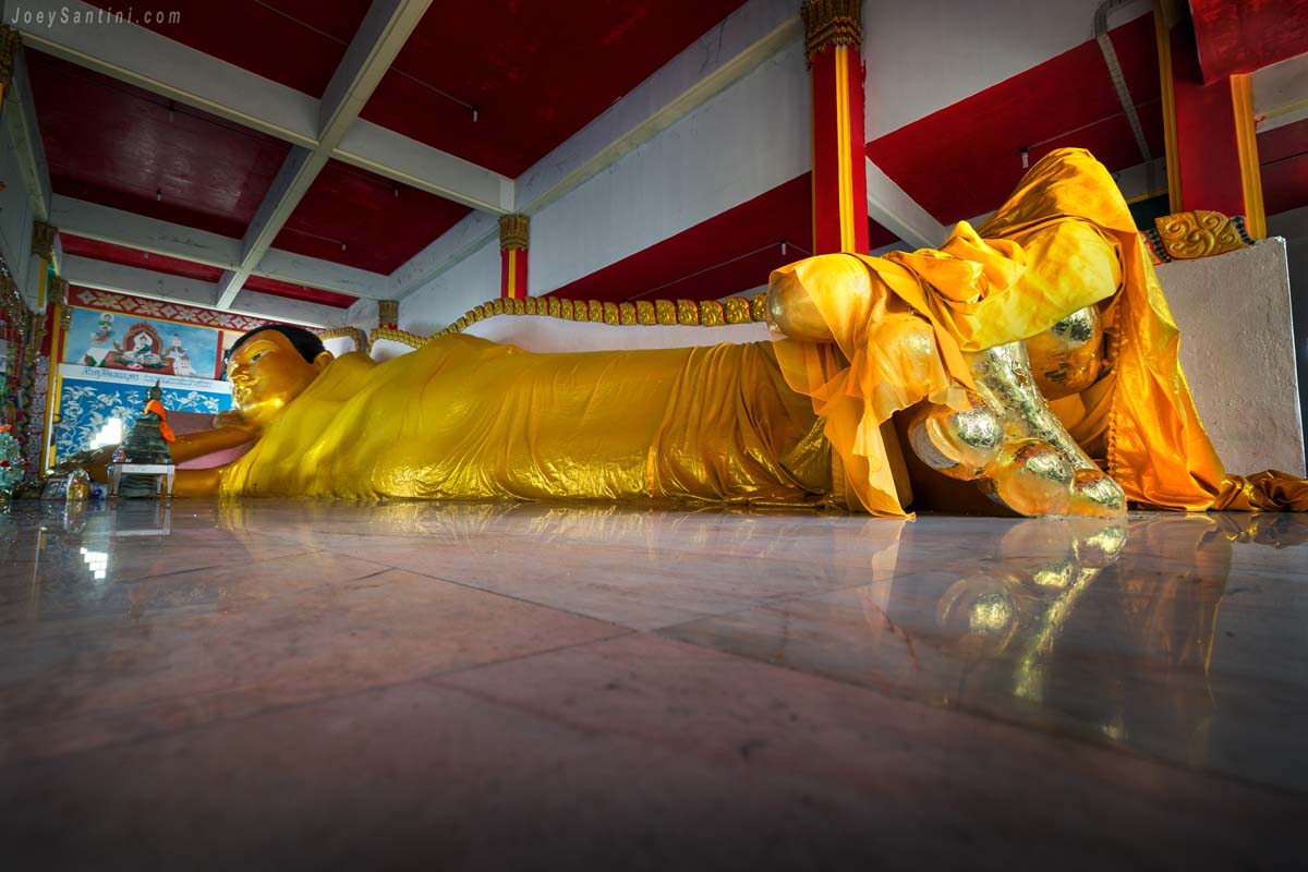 Massive golden reclining Buddha statue inside the main sanctuary at Wat Koh Siray temple in Phuket
