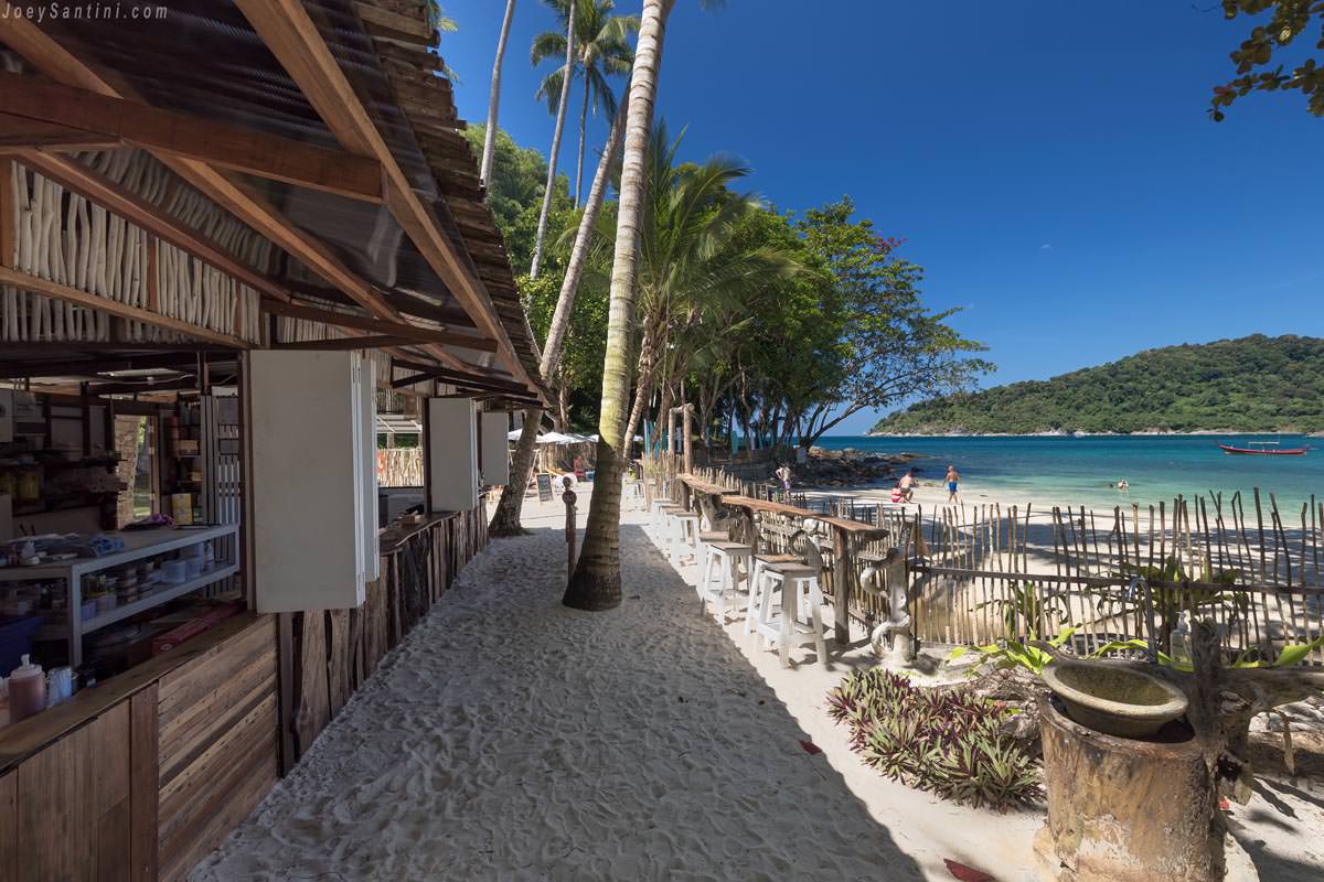 Beachfront view of Barefoot Bistro restaurant at Freedom Beach in Phuket with wooden structures and white sand.