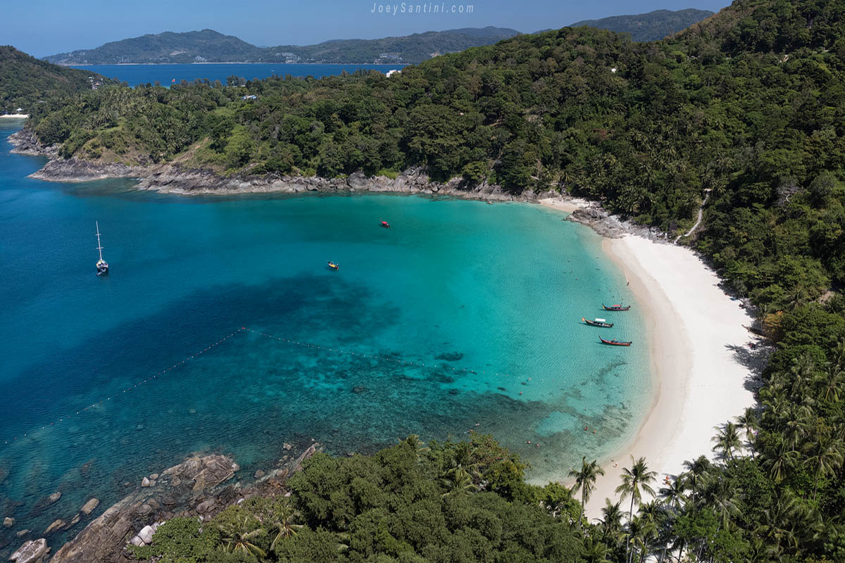 Drone aerial panoramic view of the entire Freedom Beach bay with white sand, coral reef, and tropical jungle.