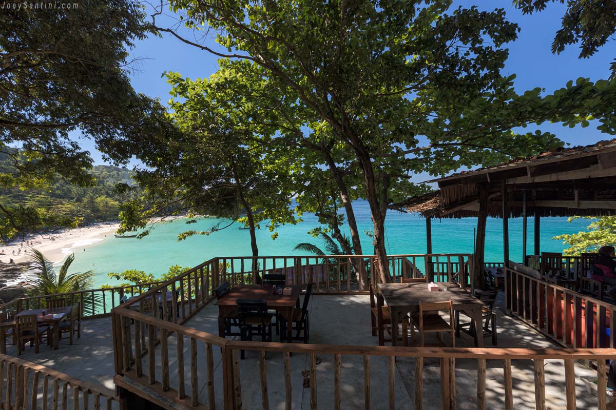 Open-air wooden dining deck of a local Thai restaurant overlooking the clear turquoise waters of Freedom Beach.