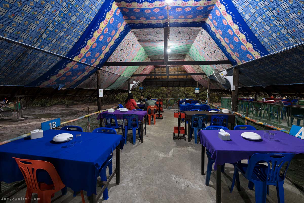 Large cabana with plastic chairs and blue cloth table with the colorful roof.