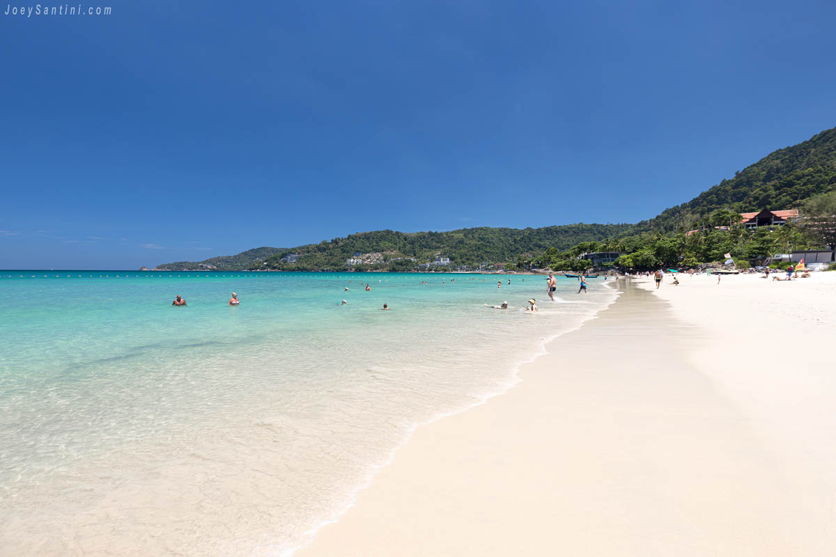 Shot of the clear sea water and white sand of Patong beach with blue sky in the background