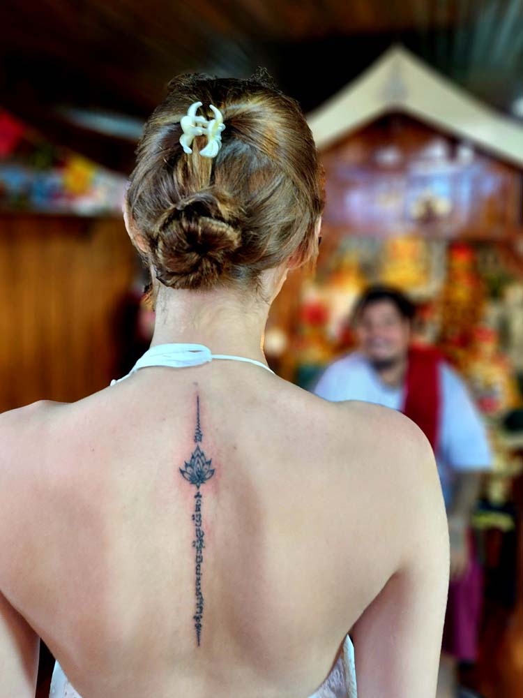 Showing a black flower tattoo and pink skin in the background