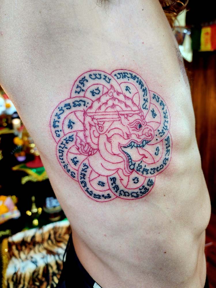 Showing a red and black lines tattoo and white skin in the background