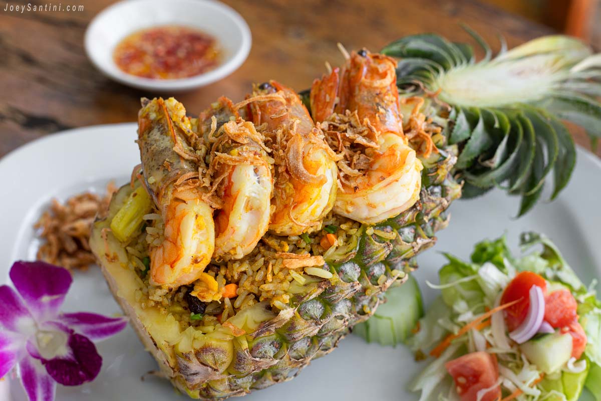 Pineapple Fried Rice served in a carved pineapple half topped with grilled prawns at Inthanin Naithon Restaurant