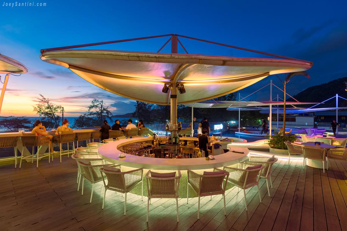 Large circular bar counter under a modern white canopy at FLY-O rooftop bar during twilight.