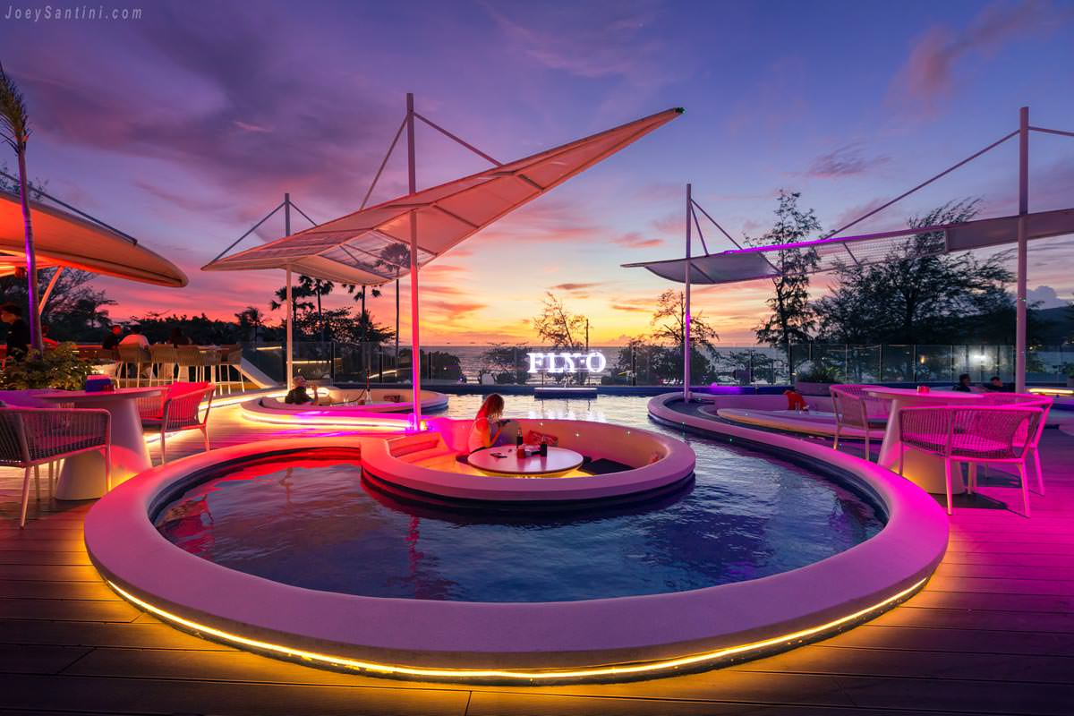 Sunken pool seating at FLY-O rooftop bar during a vibrant pink and purple sunset over the ocean.