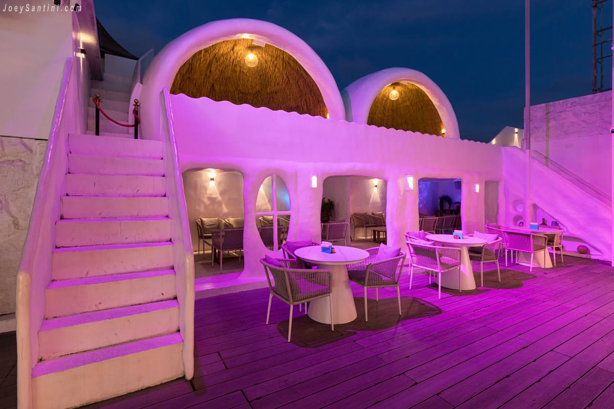 VIP seating area with Mediterranean white arches and purple lighting at FLY-O rooftop