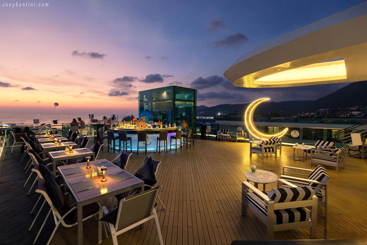 KEE Sky Lounge rooftop bar in Patong during a vibrant sunset with outdoor tables and a glowing crescent moon decoration.