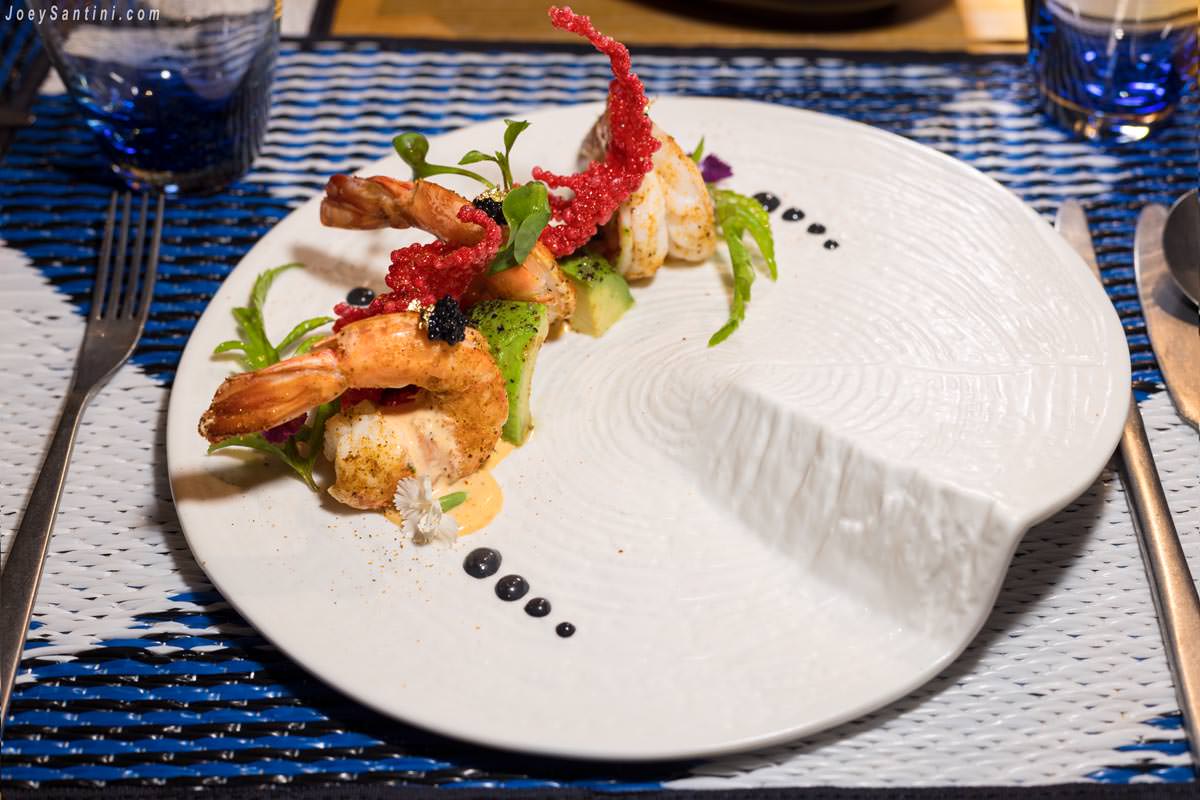 Gourmet grilled prawn appetizer with avocado and artistic culinary garnishes at Sizzle Rooftop Bar.
