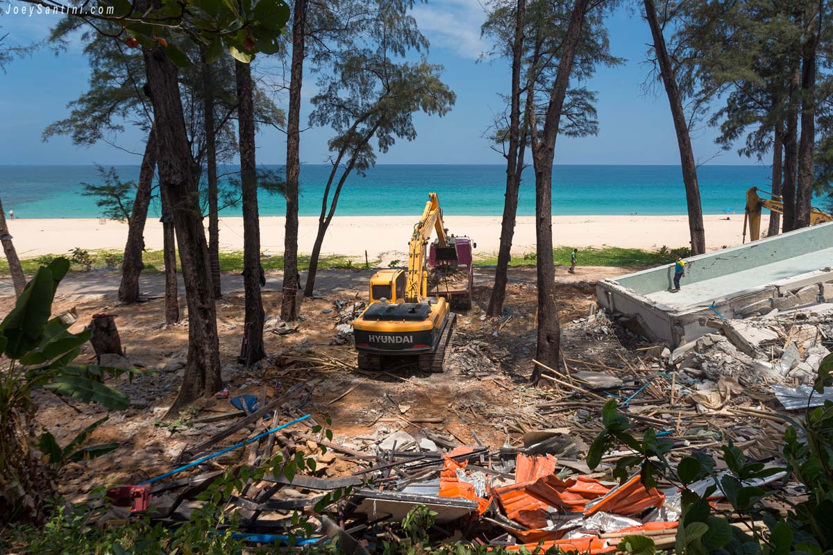 An excavator clearing debris from a demolished building on Surin Beach in Phuket