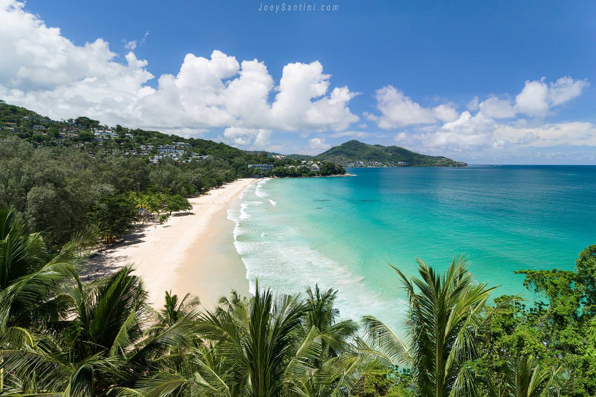 High-angle aerial drone view of the turquoise waters and white sand crescent of Surin Beach in Phuket.