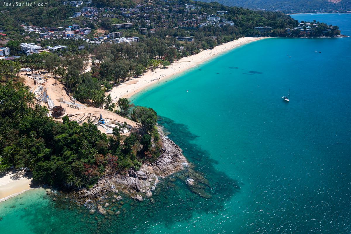 Aerial drone view of the skywalk construction project on the rocky headland of Ta-Ma Cape next to Surin Beach in Phuket.