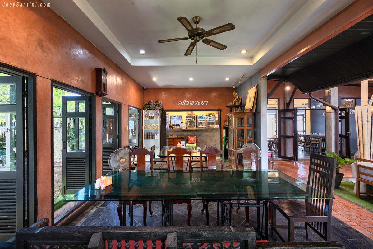 Terracotta-toned indoor dining room at Krua Praya Phuket with wooden tables and ceiling fan