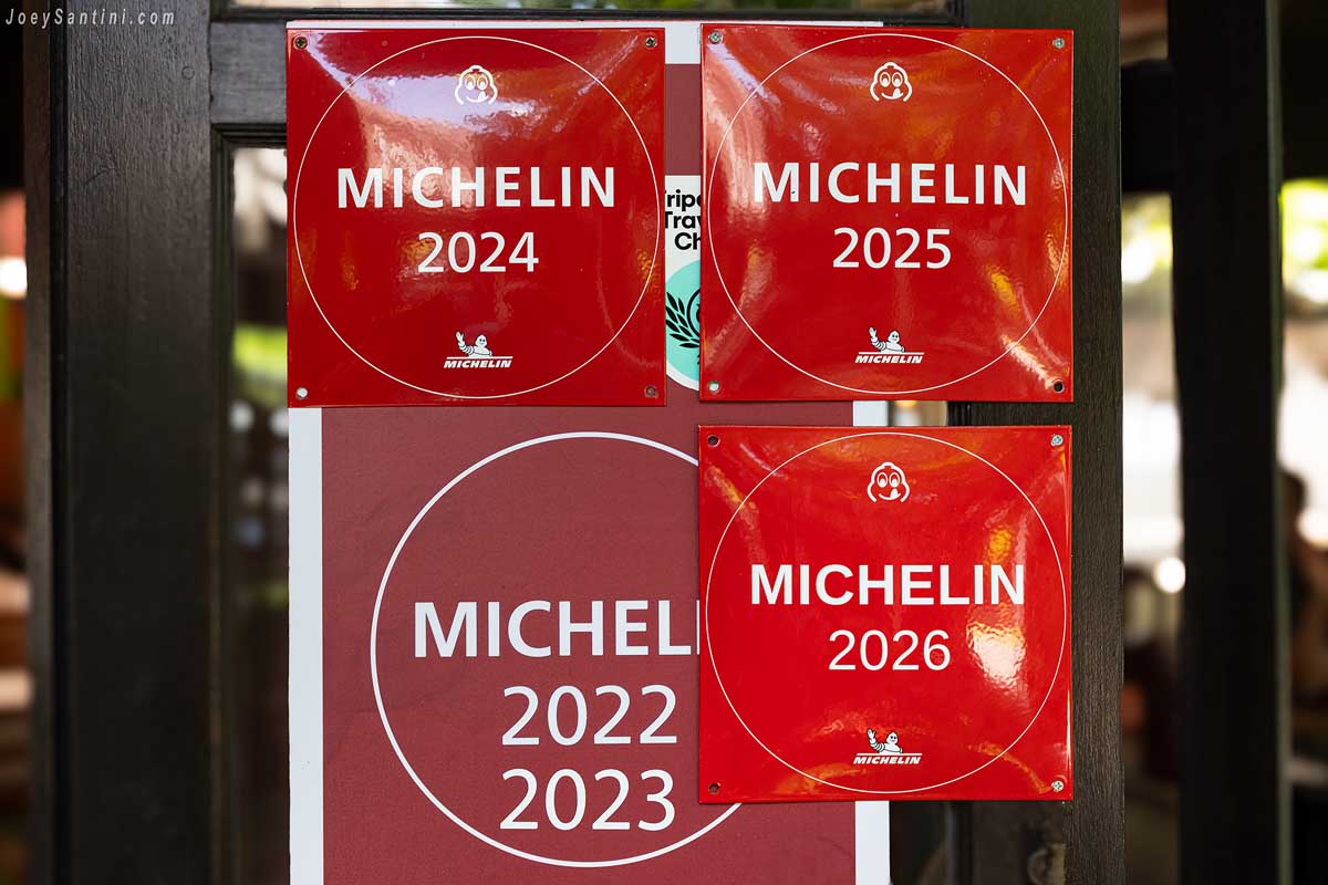 Red Michelin Bib Gourmand Guide plaques displayed on the wooden entrance door at Krua Praya Phuket