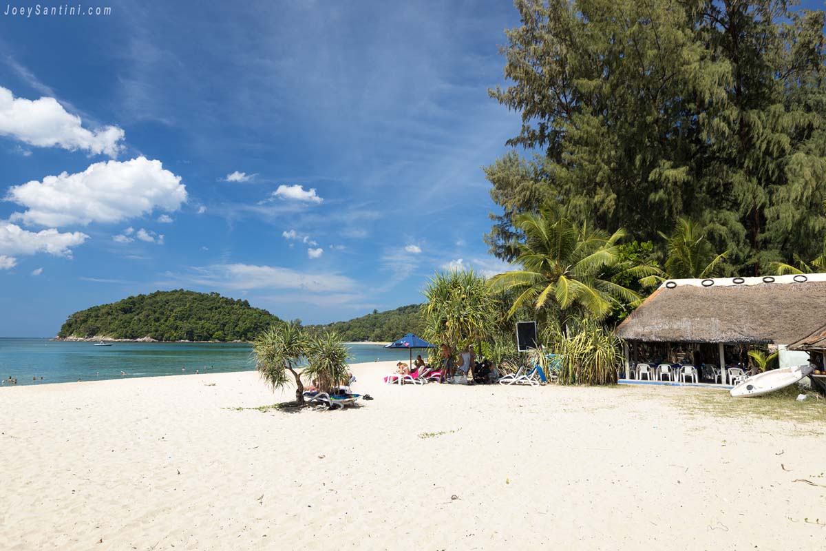 thatched roof beach hut and sun loungers on white sand at layan beach phuket