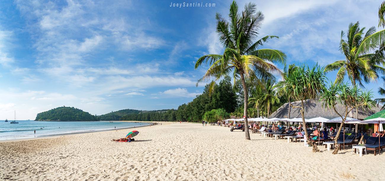 wide panoramic view of layan beach phuket with palm trees and sun loungers