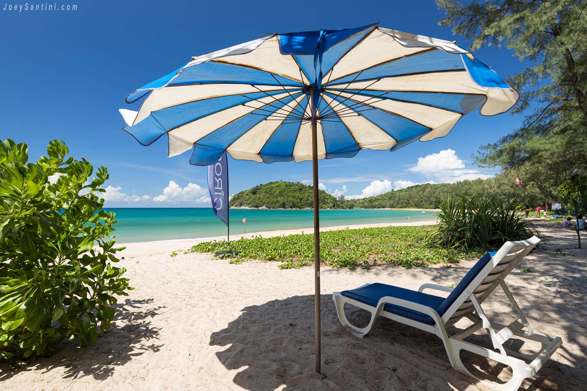Sun lounger under blue umbrella with ocean view at layan beach phuket