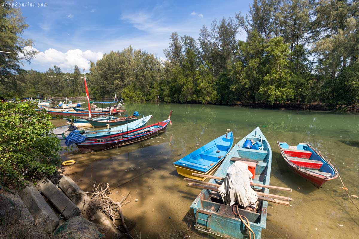 colorful wooden longtail fishing boats moored along mangrove canal at layan beach phuket