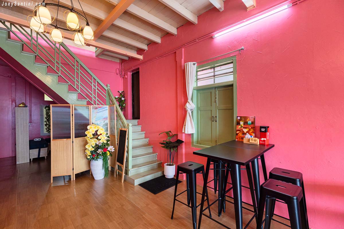 teal green staircase and high tables against pink walls at sweet come phuket