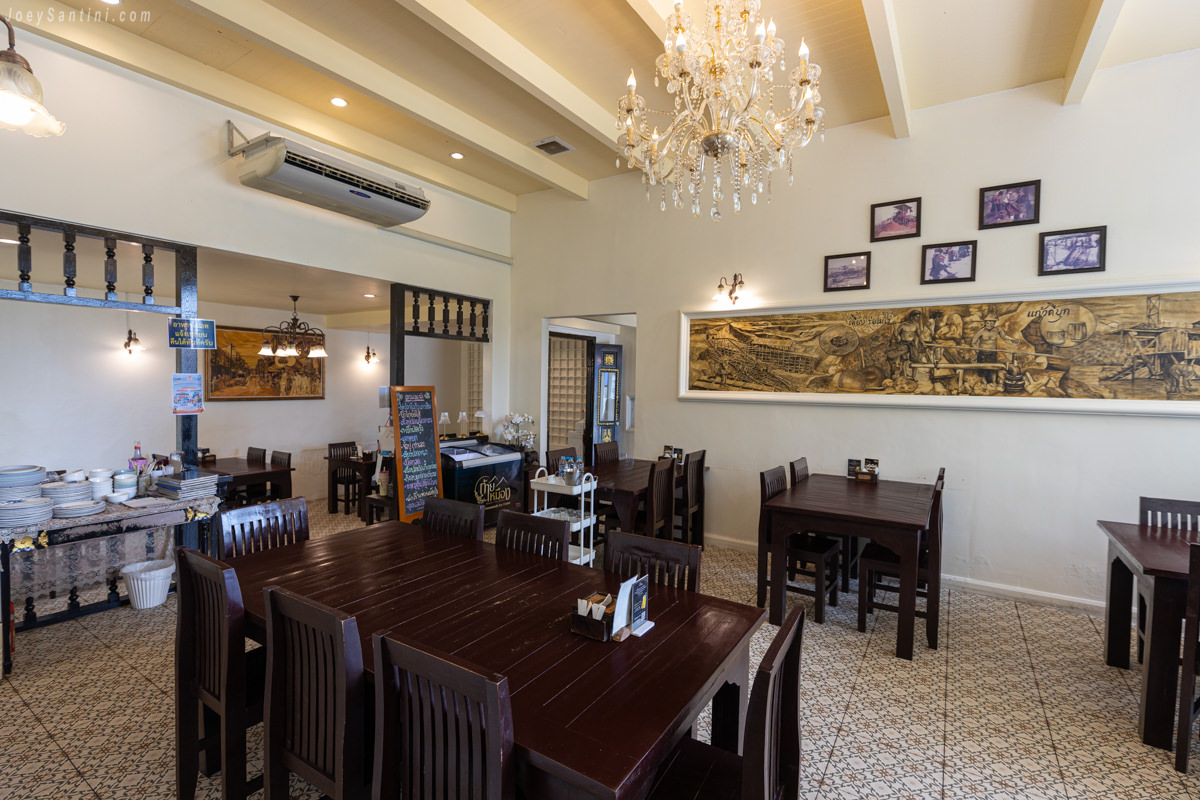 Indoor dining area with wooden tables and chandelier at Thai Mueang Phuket restaurant