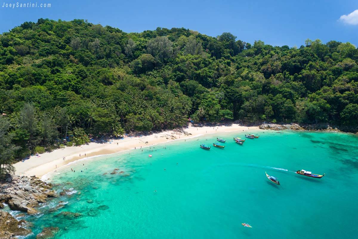 Aerial drone view of Banana Beach in Phuket showing the turquoise bay white sand and dense tropical forest