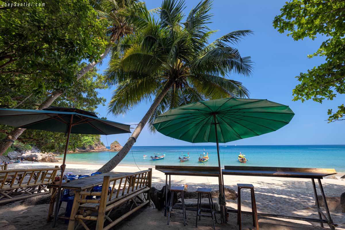 Bamboo dining tables and green parasols overlooking the turquoise sea
