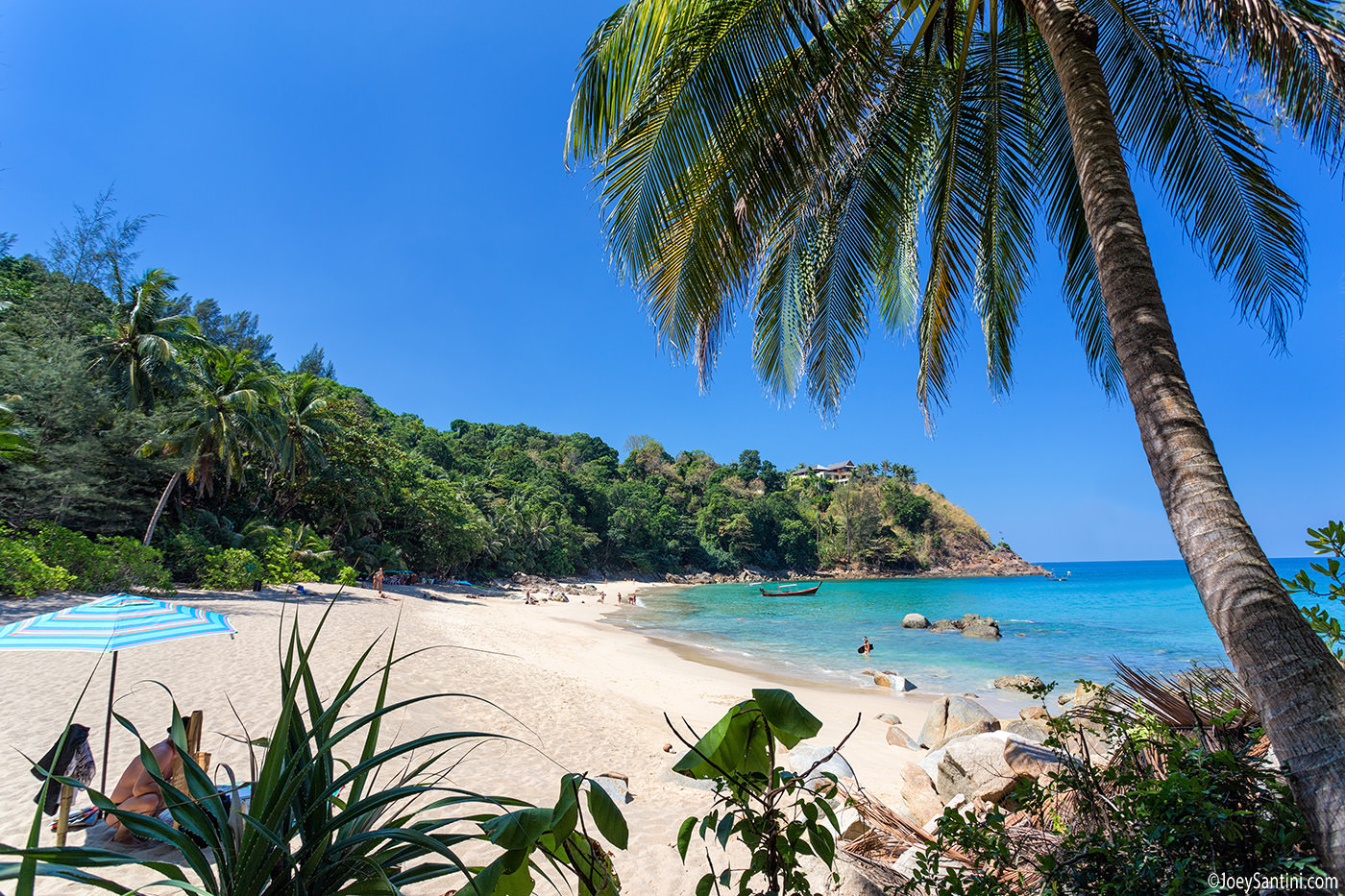 White sand and lush green jungle coastline of Banana Beach in Phuket under a clear blue sky