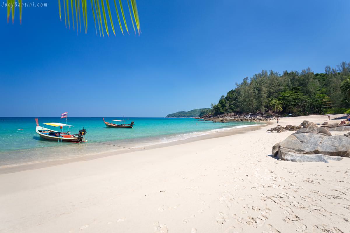 Traditional longtail boats anchored on the white sand and turquoise water of Banana Beach