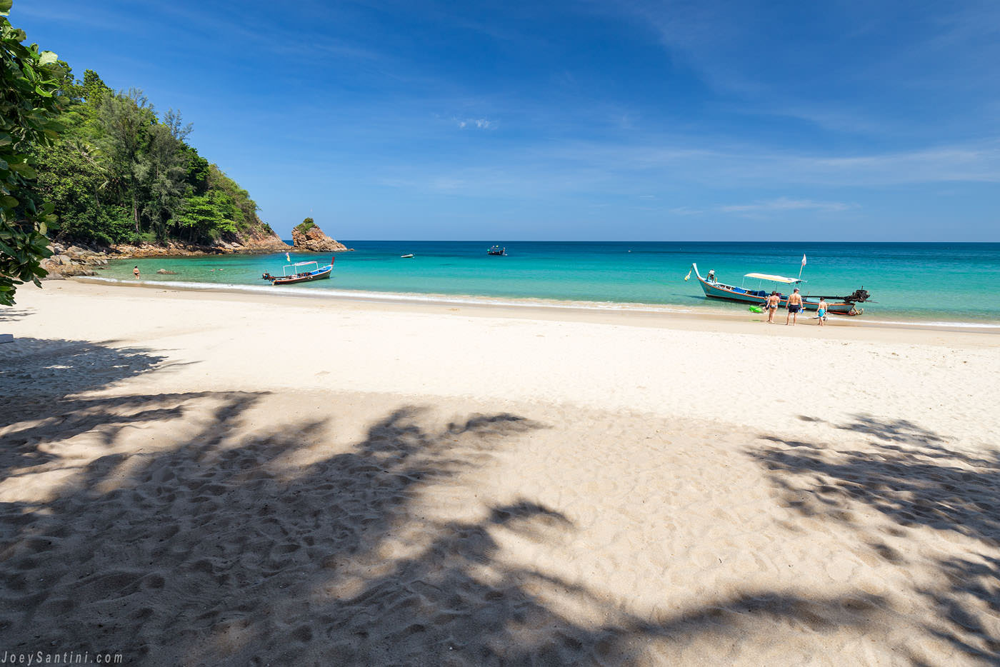 Tourists enjoying the calm tropical waters and white sand of Banana Beach